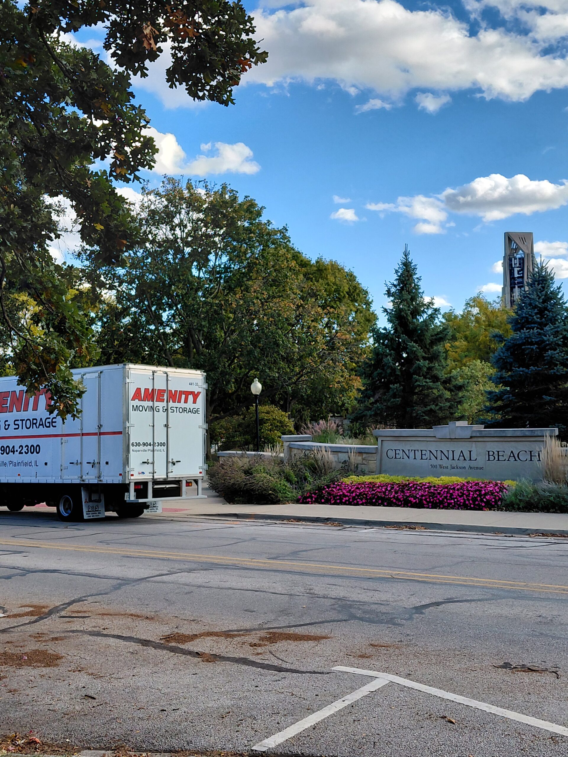 Moving truck parked near the entrance of Centennial Beach, showcasing the facility’s sign and surrounding greenery, indicating a bustling location.